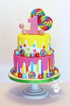 a birthday cake decorated with candy and lollipops on a pedestal for a first birthday