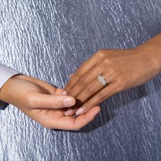 two people holding hands and touching each other's fingers with their wedding rings on them