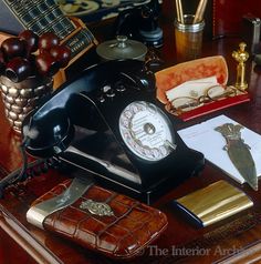 an old fashioned telephone sitting on top of a wooden desk next to other office supplies