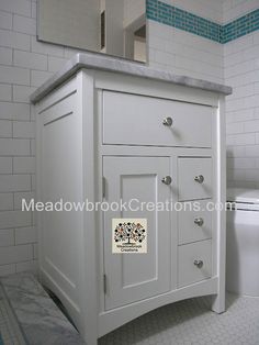 a white bathroom vanity with blue tile on the walls and floor, next to a toilet