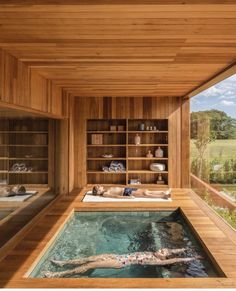 an indoor swimming pool in the middle of a wooden building with shelves on each side