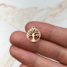 a hand holding a small gold tree charm