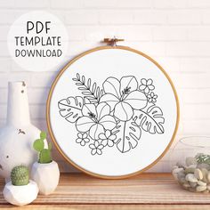 a cross stitch pattern with flowers and leaves in black ink on a white background next to a potted plant