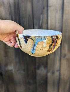 a hand holding a bowl with different colors on it