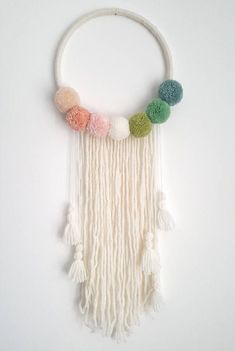 a white wall hanging with multi colored pom poms attached to it's sides