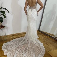 the back of a woman's wedding dress in front of a mirror with her hands on her hips