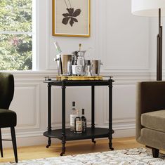 a bar cart with liquor bottles and glasses on it in front of a window next to a chair