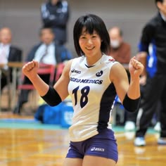 a young woman is playing volleyball on the court with her arms in the air and smiling