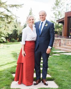 an older man and woman in formal wear posing for a photo on the lawn at their wedding