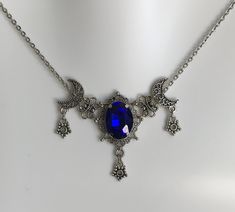 "This is a new handmade necklace. It is made with antiqued silver plated filigrees, accented with a high quality DARK BLUE glass rhinestone. Decorated portion is 2 1/2\" wide and 1 3/4\" tall in the center. Necklace is adjustable 15-18\" with a lobster clasp and chain extender. If you would like a different length, please send us a message." Gothic Blue Jewelry For Gifts, Blue Gothic Jewelry For Gifts, Blue Gothic Jewelry For Gift, Celestial Blue Necklaces, Gothic Blue Metal Jewelry, Blue Gothic Metal Jewelry, Handmade Gothic Blue Necklace, Ornate Blue Necklace With Intricate Design, Handmade Blue Gothic Necklace