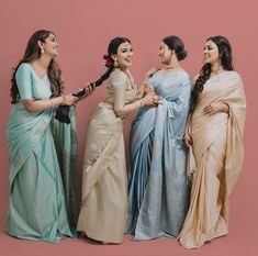 three women standing next to each other in different colored sari's and smiling