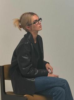 a woman sitting on top of a chair with her hair in a pony tail bun