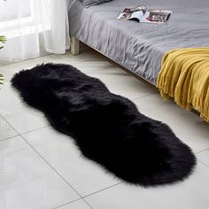 a black sheepskin rug is on the floor next to a bed