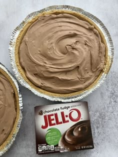 two pies with chocolate fudge and jello in them next to a box of jello