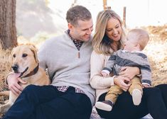 a man, woman and child sitting on the ground with a dog