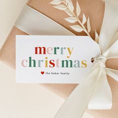 a card with the words merry christmas on it and a bow tied around it next to a wrapped present