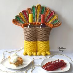 there is a crocheted turkey basket with wine bottles in it and two plates on the table