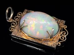 "In this one of a kind opal pendant, we've married two incredible, valuable pieces. The frame is rose gold, dating to the Victorian Era, with flowing milgrain details that give the piece an Etruscan feel! This incredible opal is one of the prettiest in our collection, featuring an incredible play of color, with flashes of orange, red and green.  Known for their green fire and amazing clarity, Ethiopian opals are prized the world over. This is a bold statement piece of the highest quality that will be treasured for years to come.  This pendant does not come with the chain shown. Please feel free to contact us, we will help you find the perfect chain for your style and budget! Metal: 14K Antique Rose Gold Gem: Ethiopian Opal 29.79 Carats  Gem Measurements: 26 x 20 mm, Oval  Measures: 50 x 24 Elegant Opal Jewelry With Large Pendant, Luxury Ethiopian Opal Formal Jewelry, Victorian Opal Jewelry For Formal Occasions, Formal Ethiopian Opal Cabochon Jewelry, Opal Necklaces, Vintage Jewellery Rings, Green Fire, Opal Pendant Necklace, Stone Feature