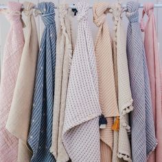 several towels hanging on a rack in front of a white wall and some other items