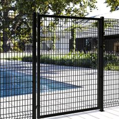 a pool behind a metal fence with trees in the background