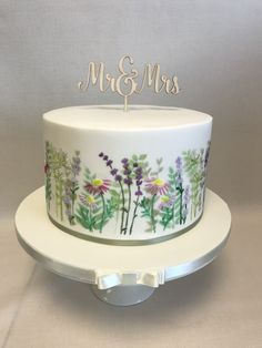 a wedding cake decorated with flowers and the word mr & mrs on top is sitting on a plate