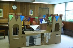 an open cardboard box sitting on the floor in front of a piano and some flags