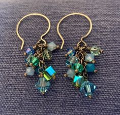 Handmade crystal cluster earrings in blues and greens. Each crystal has been hand wrapped on sterling wire and attached to a sterling chain then hung on sterling ear wires. This makes a cascade of sparkling crystals. Ear wires are also handmade and a beautiful style.  Ear wires are stamped 925.  Measures 1 3/4 inches in length including the ear wire.  Shipping includes tracking and insurance within North America. Other countries please inquire. Thank you.  To look at other items in my shop go to