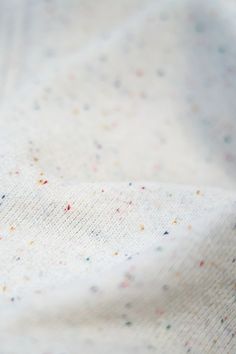 a close up view of a white fabric with multicolored speckles on it