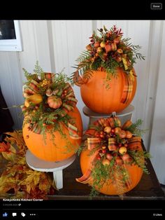 three pumpkins are stacked on top of each other and decorated with autumn leaves, berries and acorns