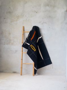 a black and orange blanket sitting on top of a wooden ladder