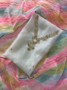 a piece of cloth that is laying on top of a bed with some gold chains attached to it