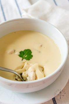 a white bowl filled with soup sitting on top of a table next to a napkin