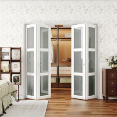 a bedroom with white walls and wooden floors, two glass doors open to reveal a walk - in closet