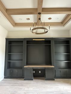 an empty room with built in cabinets and a chandelier hanging from the ceiling