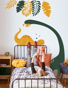 a child laying on top of a bed in front of a wall mural with an elephant