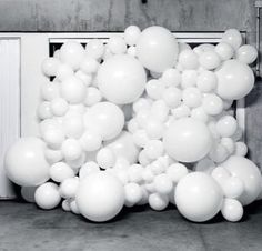 white balloons floating in the air next to a wall