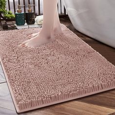 a person's feet on a pink rug in front of a bathtub