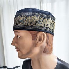 Men's Black Cotton Kufi/Fez, Drumming Cap with Wide Elephant Trim  ~  Tubeteiki, Kazakhi, Drumming cap.  This is made from a cotton spandex fabric. Men's and Woman's Cap ~  This little cap is designed to just cover the top of the head. It sits above the ears. It measures 3 inches deep. This trim is 2 7/8 inch wide with marching elephants (trunk up for luck) This trim pretty much covers the entire bottom of the hat. Tan and gold embroidery with gold metallic highlights on a black field. It is con Traditional Adjustable Black Turban, Adjustable Black Traditional Turban, Elephant Trunk Up, Gold Embroidery, Skull Cap Beanie, Caps For Women, Skull Cap, Spandex Fabric, Bristol