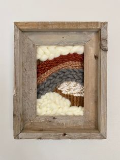 an old wooden frame with different colored yarns in it and a white wall behind it