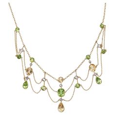 An antique, peridot, citrine, white sapphire and gold festoon necklace, with round, cushion and drop shaped faceted peridots and citrines, in gallery claw settings, and white sapphires, in millegrain edged rub over settings, in knife edge pendants, on a trace chain, with finer, trace chain festoons, with a barrel clasp, engraved with 15, for 15ct gold, with inventory number a8609 scratched on a pendant, circa 1890. Approximate Measurements: Length 388mm, longest drop 39mm Festoon Necklace Vintage, Spring Court, Festoon Necklace, Victorian Jewellery, Yellow Gems, Peridot Necklace, Layer Necklace, Gem Necklace, Antique Necklace