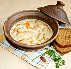 a wooden bowl filled with soup next to a slice of bread on top of a table