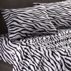 a bed with zebra print sheets and pillows