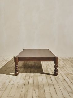 a wooden table sitting on top of a hard wood floor next to a white wall