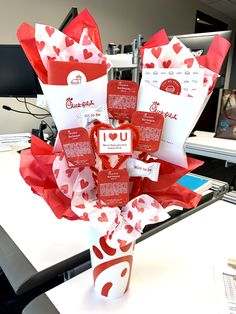 a vase filled with lots of red and white hearts on top of a table next to a computer