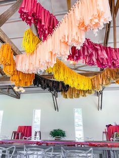 colorful streamers hang from the ceiling in an open space with chairs and tables underneath