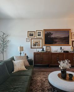 a living room filled with furniture and framed pictures on the wall above a coffee table