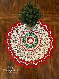 a crocheted doily with a small christmas tree in it on a wooden floor