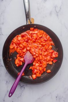 a frying pan filled with food and a purple spatula on top of it