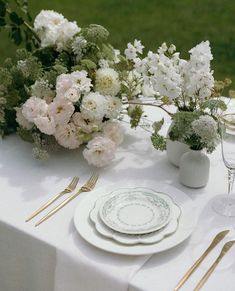 the table is set with white plates and silverware, flowers in vases, and gold cutlery