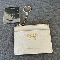 a white purse with a gold bow on it and a card holder next to it